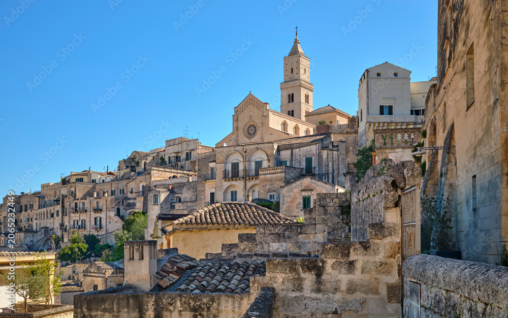 Fototapeta premium street view in the medieval city of Matera, Basilicata, Italy, featuring historic stone buildings, ancient architecture, under a clear blue sky in the UNESCO World Heritage