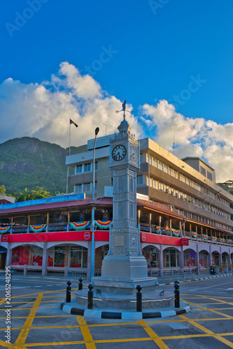 The newly restored Victoria Clock Tower stands proudly in the town centre of Mahé, Seychelles. This iconic historical landmark is adorned with national flags against a beautiful tropical backdrop