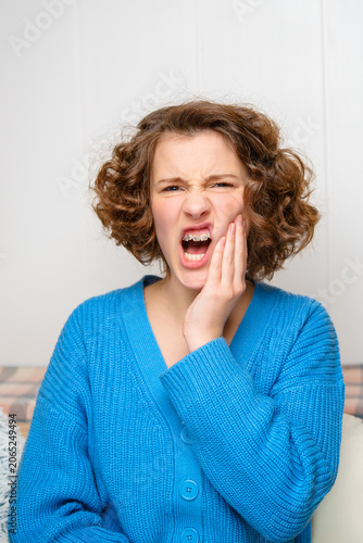 young woman with severe toothache suffering from dental pain and discomfort, holding her jaw and grimacing due to oral health problems and urgent need for dental care