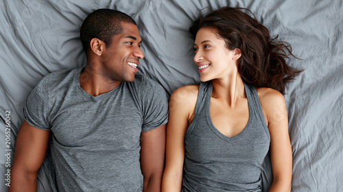 Young couple mixed race couple bed gray shirt smile eye contact intimacy bedroom happy relationship Young couple gray shirt bed sharing smile and eye contact, relaxed intimacy and happy mood cozy