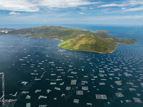 Aerial landscape of a rugged island encircled by floating aquaculture structures in the sea near Song Cau town.