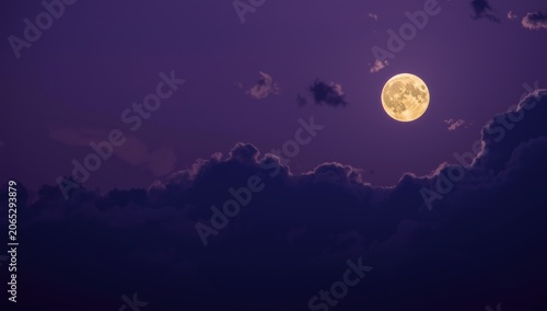 Full moon rising over cloudy purple sky