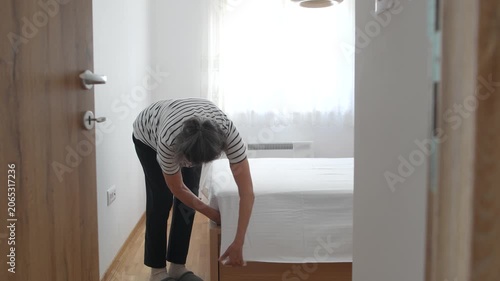 Elderly woman putting fresh bed linen