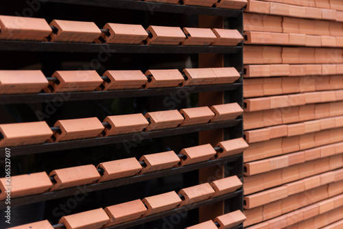 Close-up of contemporary architectural details featuring repeating rows of orange clay bricks installed on a metal frame.