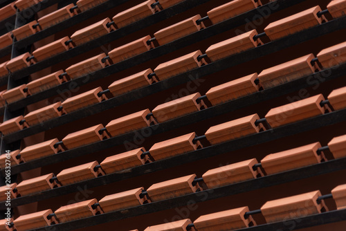 Close-up of contemporary architectural details featuring repeating rows of orange clay bricks installed on a metal frame.