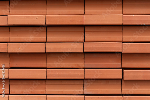 Close-up of contemporary architectural details featuring repeating rows of orange clay bricks installed on a metal frame.