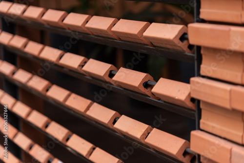 Close-up of contemporary architectural details featuring repeating rows of orange clay bricks installed on a metal frame.