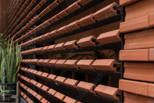 Close-up of contemporary architectural details featuring repeating rows of orange clay bricks installed on a metal frame.