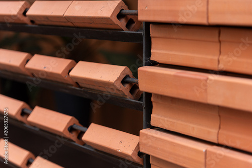 Close-up of contemporary architectural details featuring repeating rows of orange clay bricks installed on a metal frame.