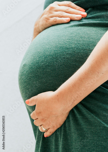 Bild auf Leinwand Close Up of Pregnant Woman Belly in Green Dress Vertical Portrait