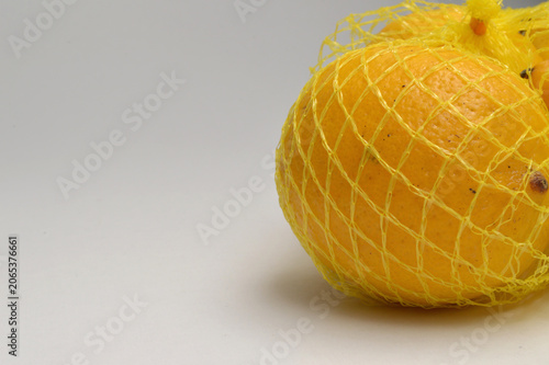 yellow lemon in a yellow mesh  on a white background corner composition horizontal layout, lemons close up with generous copy space,