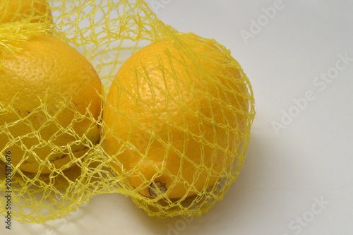 yellow lemon in a yellow mesh  on a white background corner composition horizontal layout, lemons close up with generous copy space,