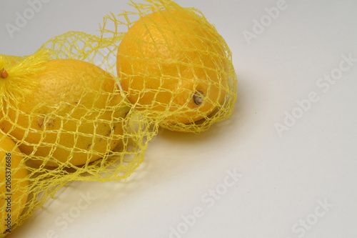 yellow lemon in a yellow mesh  on a white background corner composition horizontal layout, lemons close up with generous copy space,
