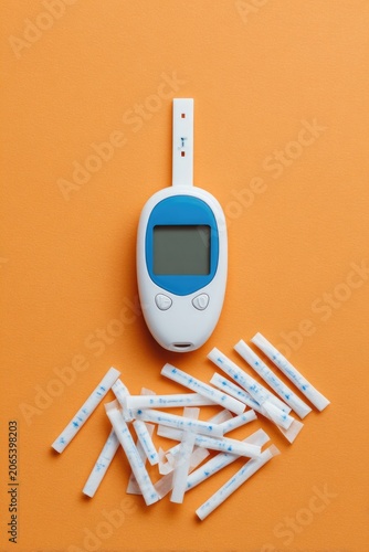 Diabetes Monitoring Device with Test Strips on Orange Background.