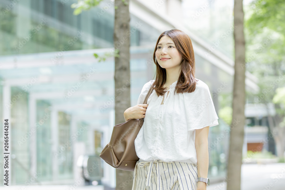 Fototapeta premium 緑豊かなオフィス街を歩く日本人女性のライフスタイル