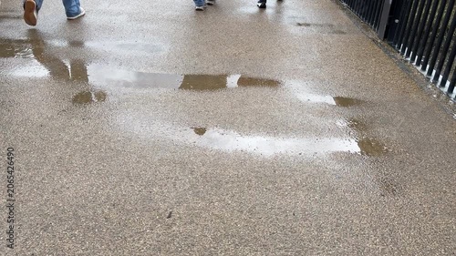 View of legs of people walking behind them on the bridge. Wet after rain, walking background plate.