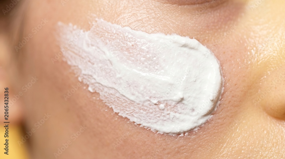 Fototapeta premium Close up of thick white cosmetic cream or healing ointment smeared on cheek