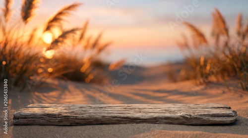 Weathered wood log podium on sandy beach dunes at sunset for natural organic product display mockup background image