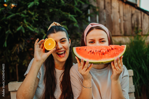 Happy young women enjoying summer fruit outdoors
