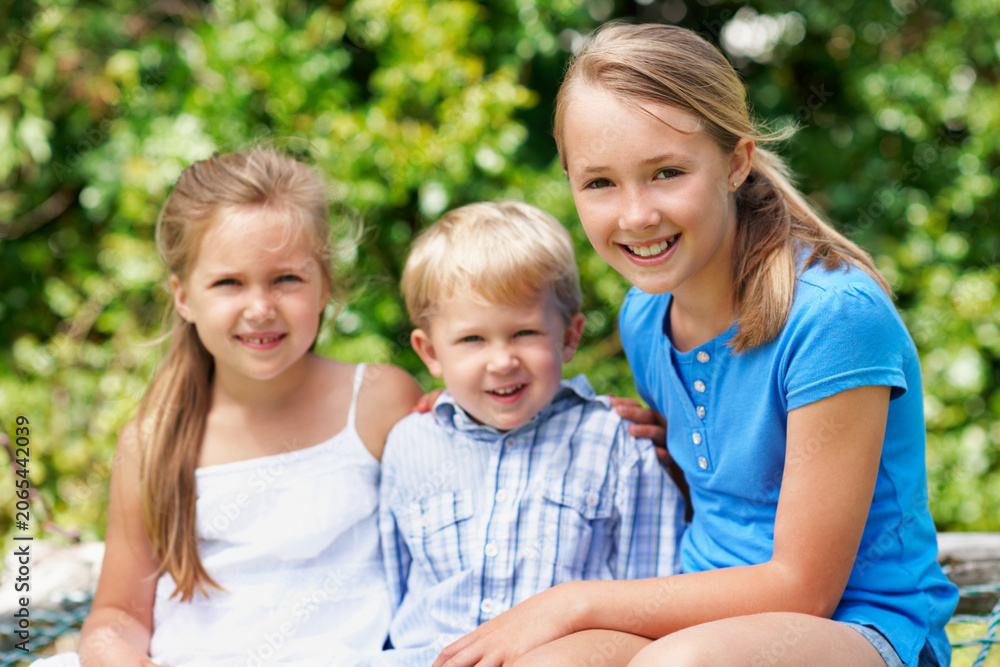 Fototapeta premium Family, children and portrait in park with love, sibling care and relationship development with smile. Boy, sisters and outdoor with happiness for support, bonding and together for summer holiday