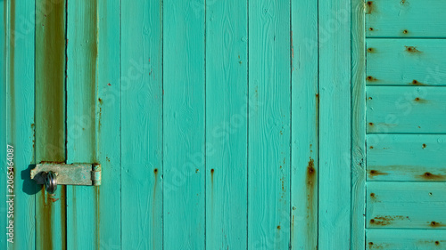 Photos Weathered turquoise wooden door with rusty lock on breach hut door