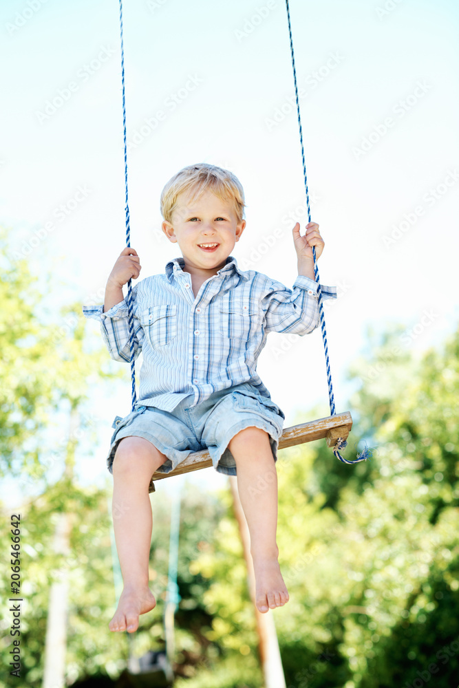 Fototapeta premium Child, portrait and play on swing at playground, fine motor skills and development in nature and fun. Outdoor, park and kid with smile on weekend, growth and boy with positive attitude or fresh air
