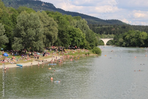 People cooling off at a river beach with inflatable floats on a hot summer day