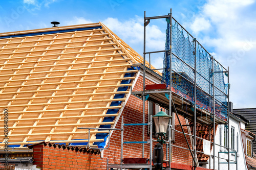 Renovation of a pitched roof with timber battens, roof membrane and scaffolding on a brick house