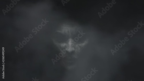 Scary ghost face appearing from thick dark smoke, creepy demon face in fog for halloween background