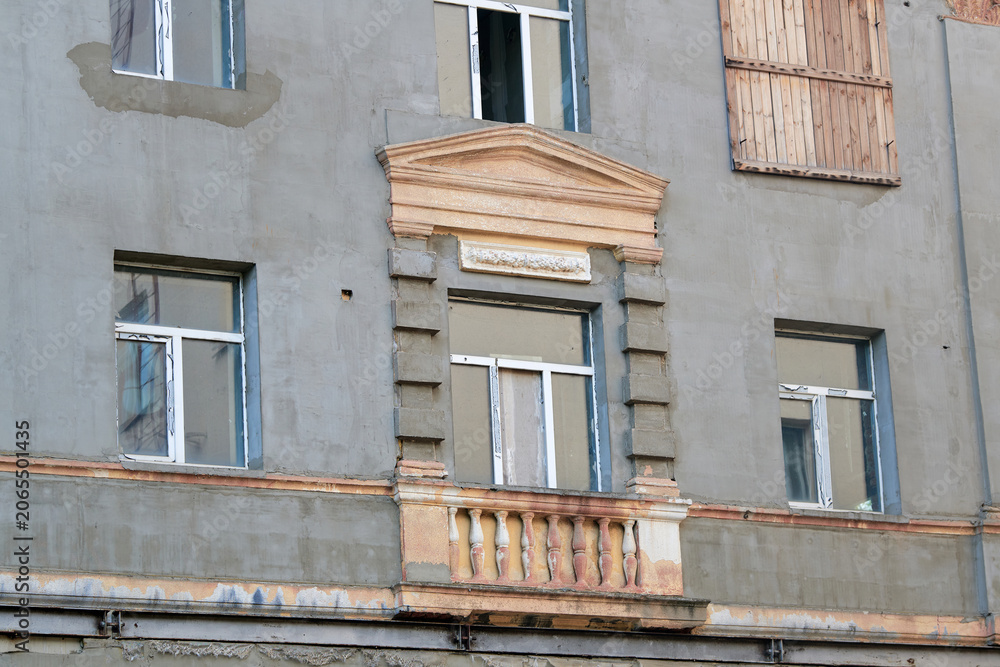 Naklejka premium Weathered building facade during restoration works, horizontal steel support reinforcement beam. Building facade wall under restoration, decorative classical window frame with triangular pediment