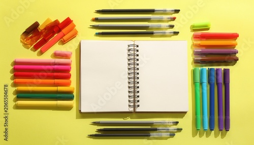 Colorful Art Supplies Arrangement with Blank Notebook on Bright Yellow Background for Creative Inspiration and Artistic Projects