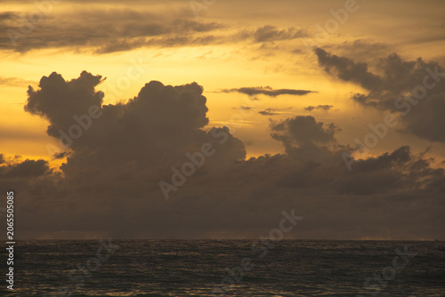 Tableau sur toile Golden sunset over calm sea with dramatic clouds and colorful sky reflected on w