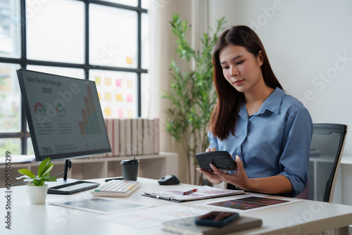 Foto Young Asian female accountant analyzing financial data and calculating business