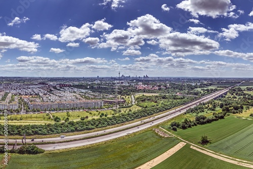 Wide aerial panorama of Frankfurt skyline above countryside and motorway