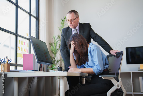 Photography Stressed businesswoman covering her face at an office desk while an angry male b