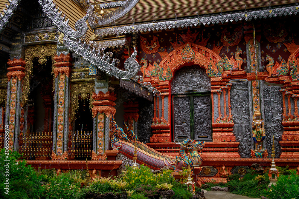 Fototapeta premium Beautiful architectural features of a classic thai temple embraced by vibrant lush greenery