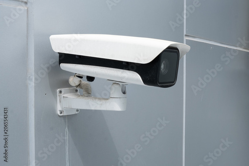 Fotografie white surveillance camera is mounted on gray wall for monitoring