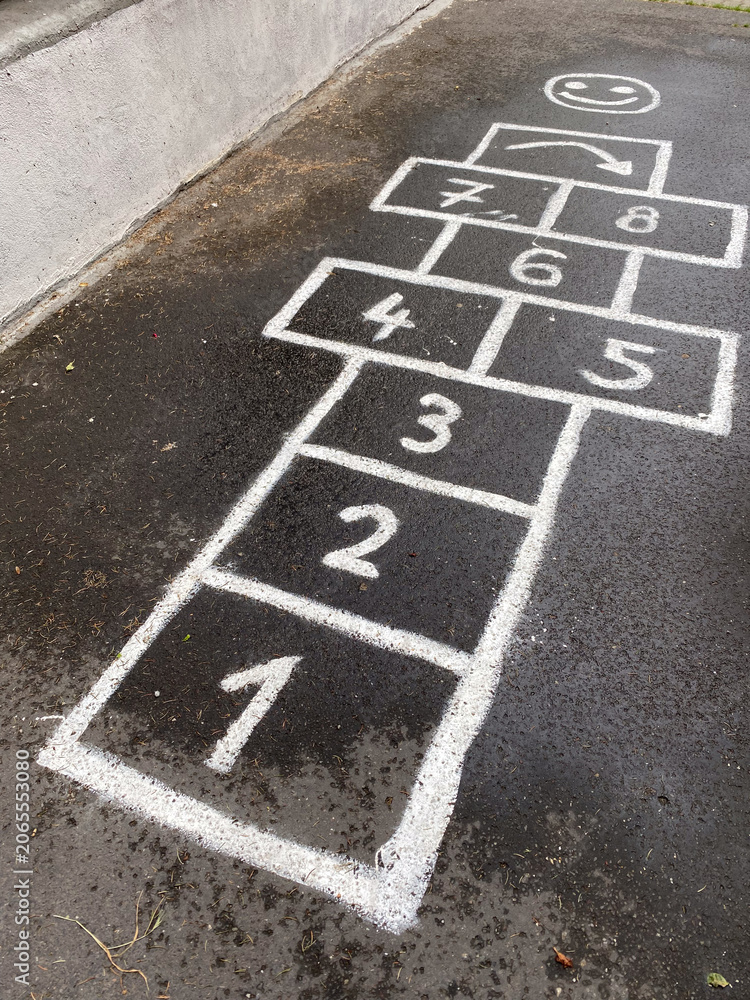Fototapeta premium Traditional hopscotch game drawn with white chalk on wet dark asphalt.