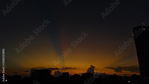 Canvas Print Golden sunset over city skyline silhouette with dramatic crepuscular rays in the