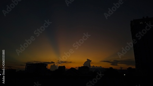 Fotografi Golden sunset over city skyline silhouette with dramatic crepuscular rays in the