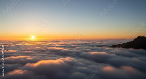 Sunrise over thick clouds with mountain peak emerging from mist aerial view