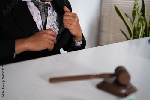 Dishonest businessman puts money, US dollars, into his coat pocket in the dark - the concept of corruption and embezzlement and bribery.
