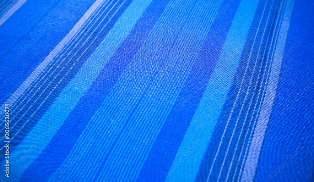 Obraz premium Close-up diagonal perspective view of traditional Indonesian woven sarong fabric with selective focus on blue striped patterns