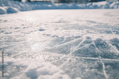 Close up of textured ice surface on an outdoor rink with visible skate marks glistening in bright sunlight on a clear winter day