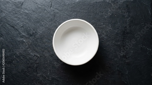Empty white bowl on black slate texture