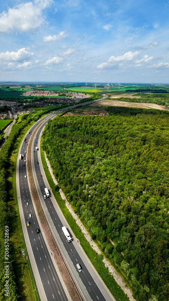 Obraz premium Aerial vertorama of a UK Motorway cutting through woodland countryside