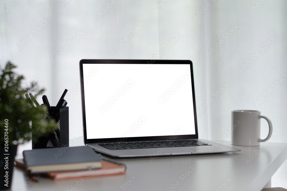 Fototapeta premium Laptop with Blank White Screen on Clean White Desk Workspace with Coffee Mug, Pens, and Plant