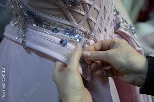 Bild auf Leinwand The designer is sewing a pink evening gown (stock photo)