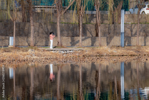 People walking and taking photos on riverside boardwalk in vibrant spring park