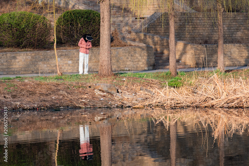 People walking and taking photos on riverside boardwalk in vibrant spring park